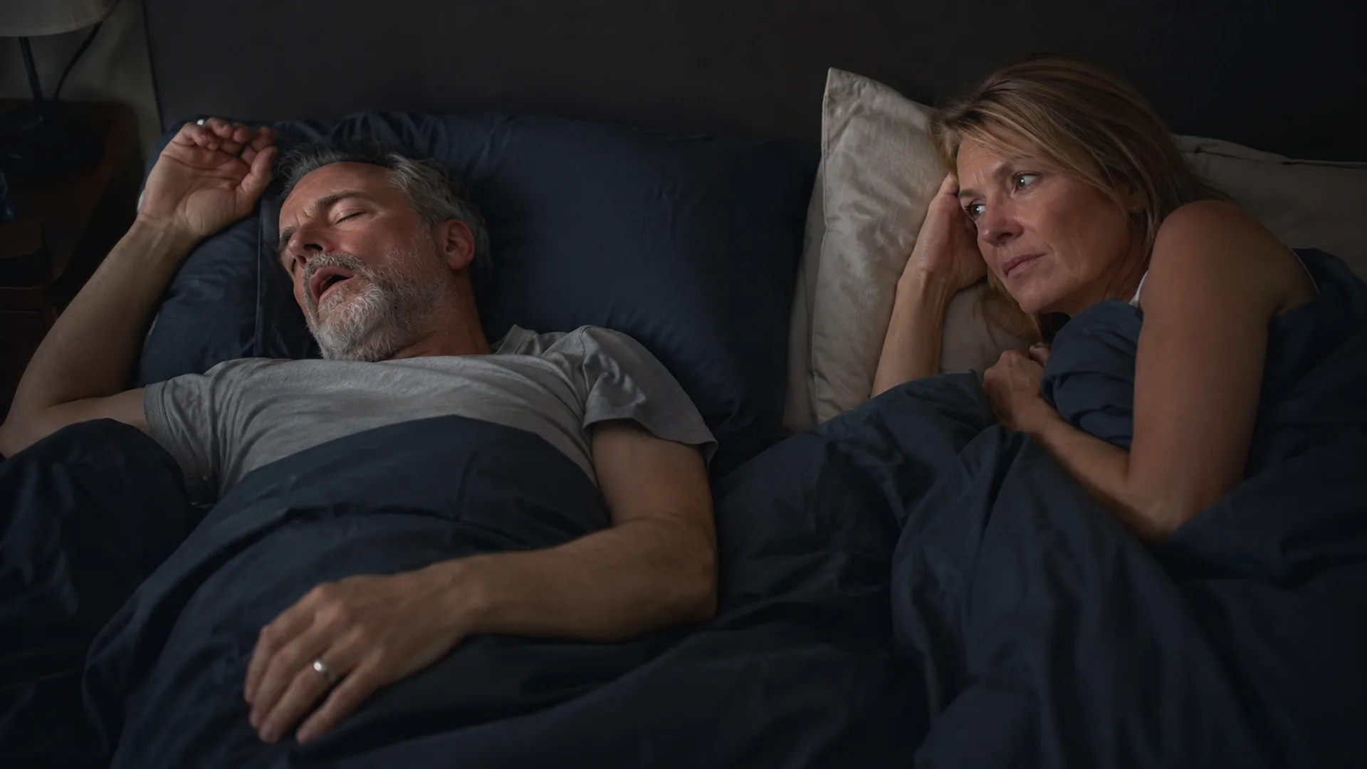 Man snoring while sleeping beside his partner